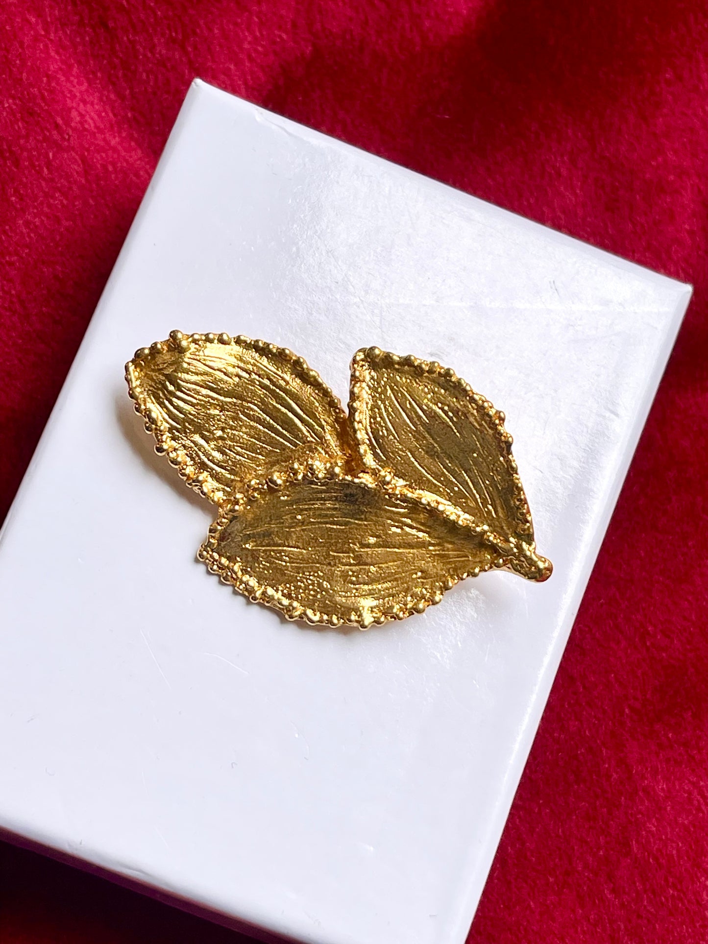 Vintage Yves Saint Laurent 80s 90s gold tone leaf brooch excellent condition on white and red background