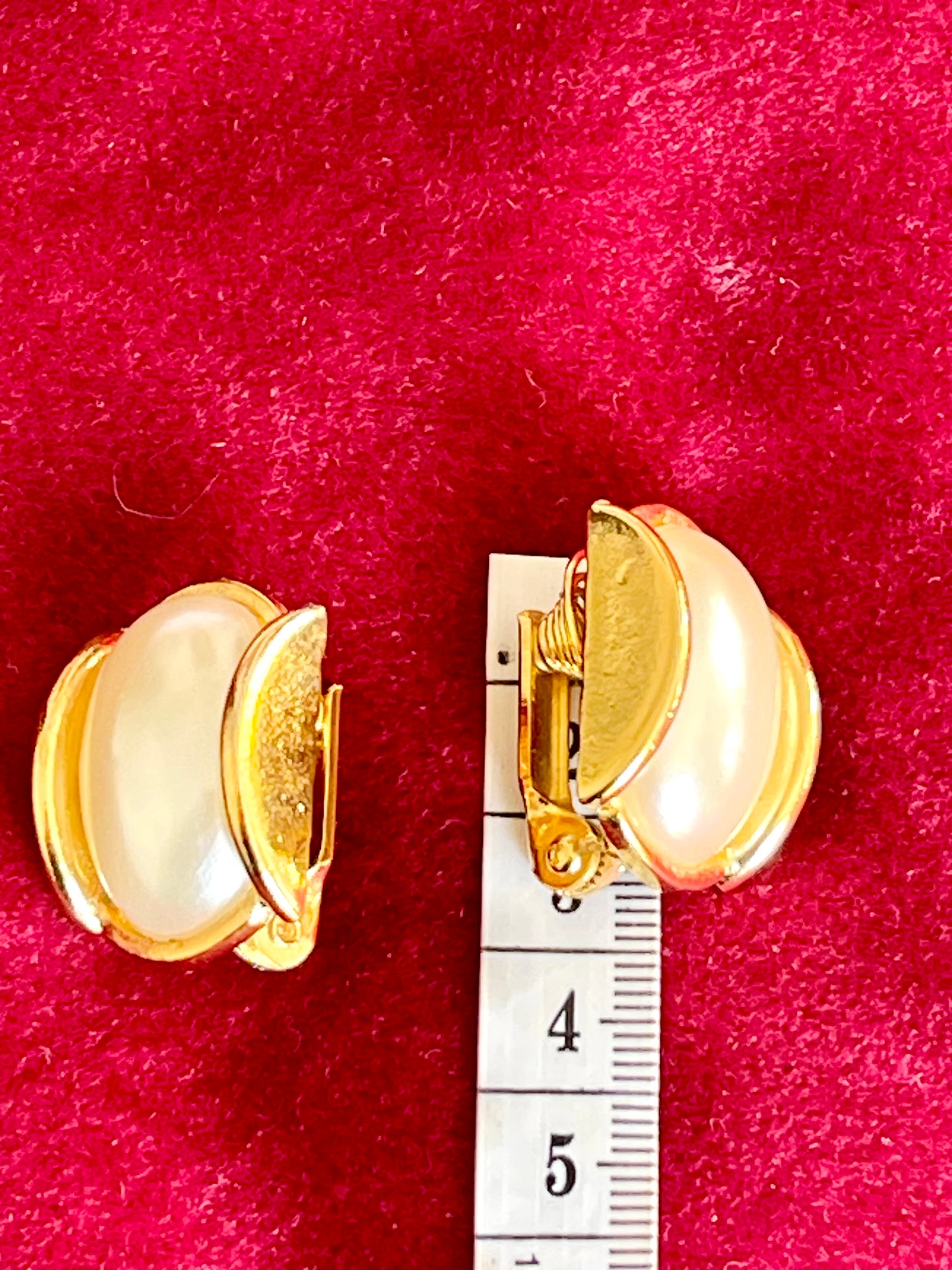 Pair of vintage gold-plated clip-on earrings with faux pearls displayed on a red velvet surface next to a measuring tape showing approx. 3.5 cm length.