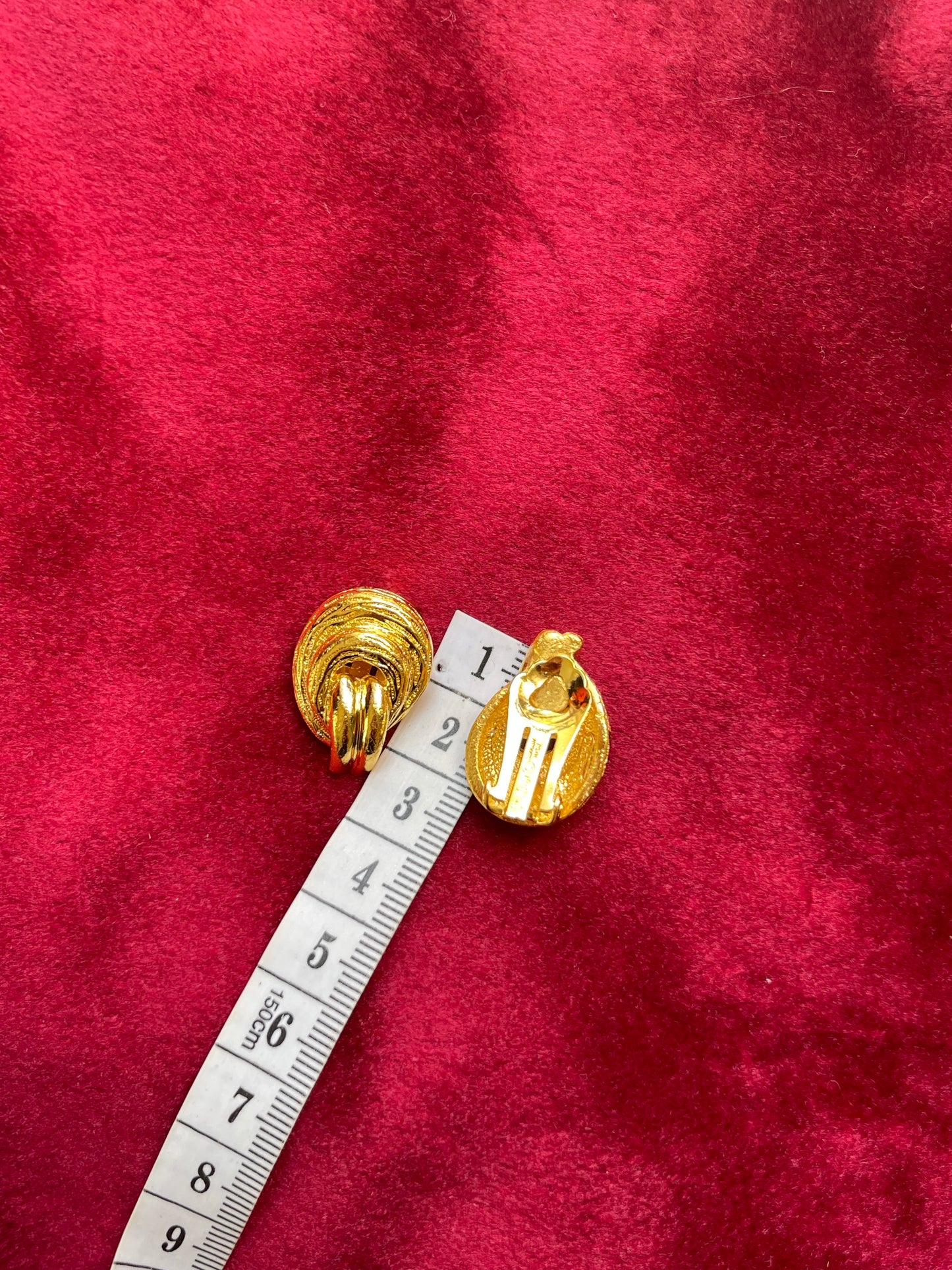 Measuring 2.2 cm Vintage Christian Dior clip on Dior earrings, gold plated 18KG displayed on a red velvet background using a measuring tape