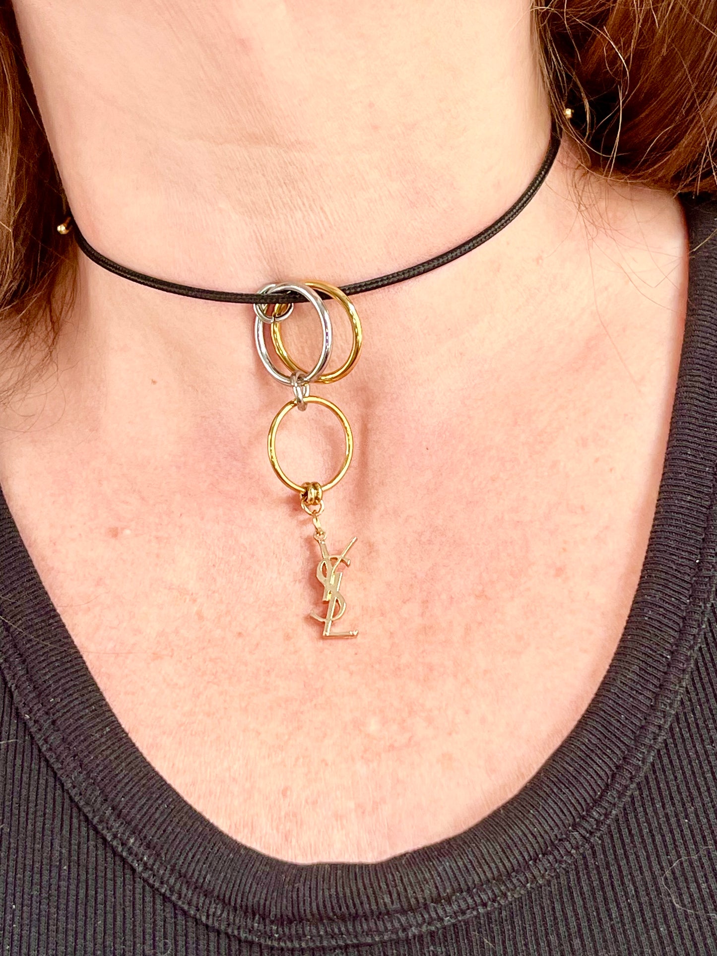 close up view Yves Saint Laurent authentic charm as a ring pendant and bracelet with magnetic black cord stainless steel gold silver tone