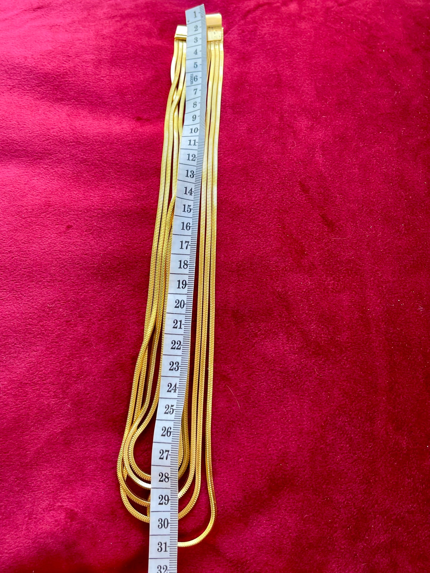 Vintage Yves Saint Laurent gold multi-strand necklace laid flat on red velvet background with measuring tape showing 31 cm length