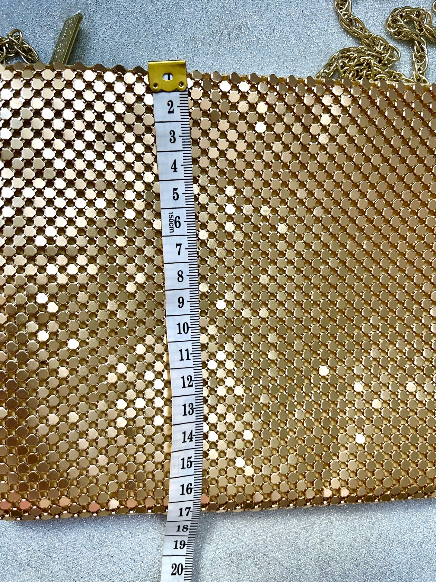 Using a measuring tape to show length of Paco Rabanne gold pixel metal vintage crossbody bag
