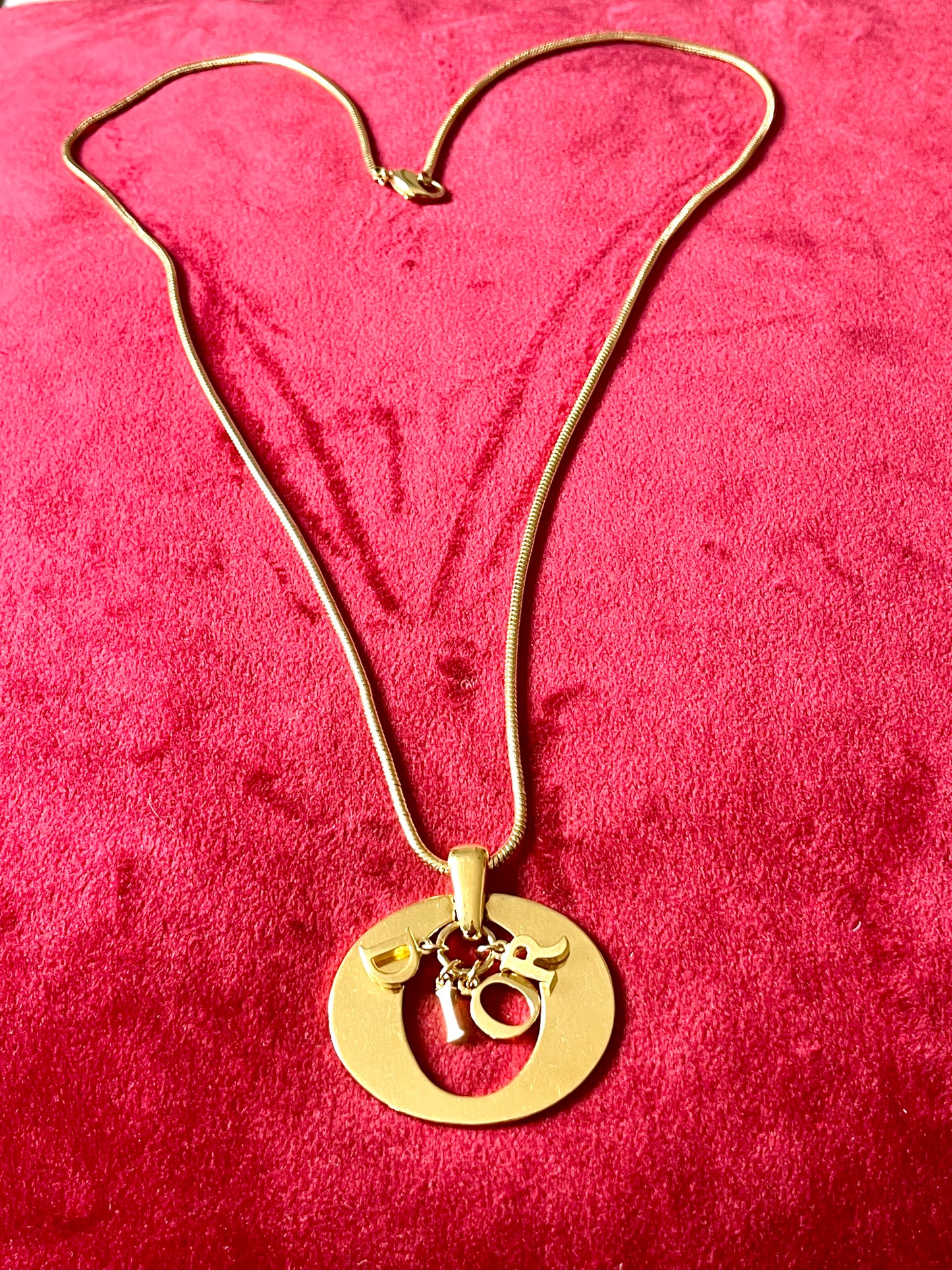 Vintage Christian Dior charm necklace in gold-tone metal, featuring bold logo pendant. Circa late 1990s.