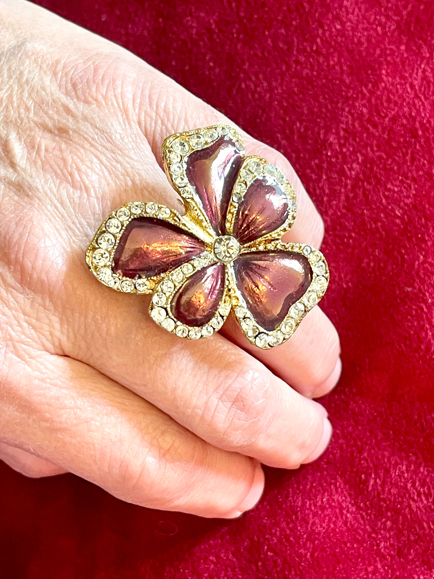 Yves Saint Laurent vintage floral ring on hand, featuring metallic pink enamel petals and crystal accents