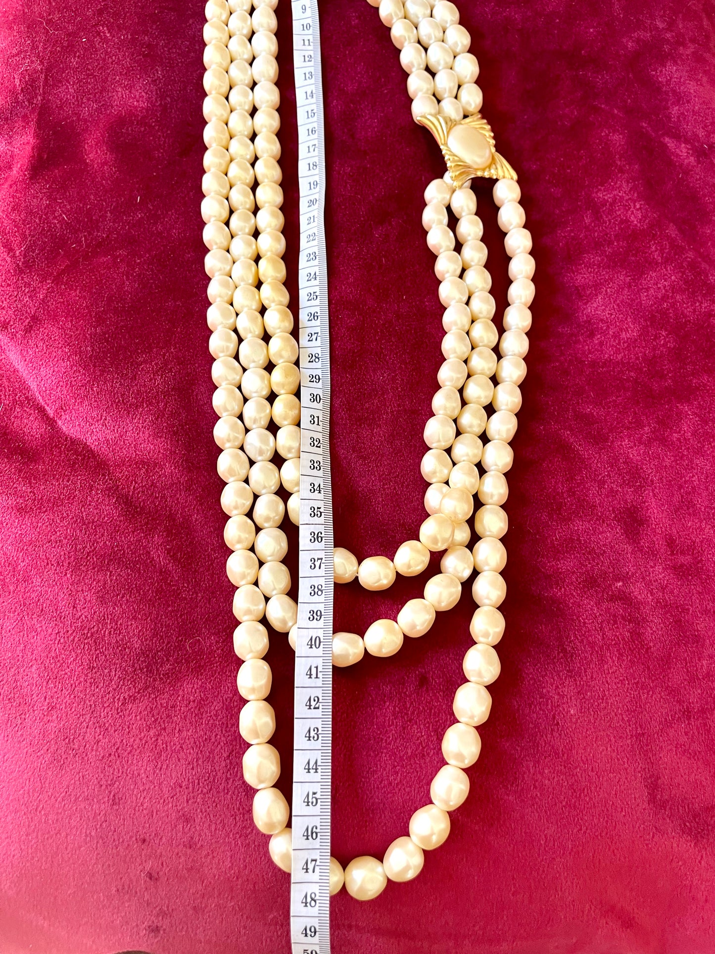 Length 48 cm of YSL faux pearl necklace clasp on red velvet background highlighting the gold-tone sculptural design and domed pearl centerpiece