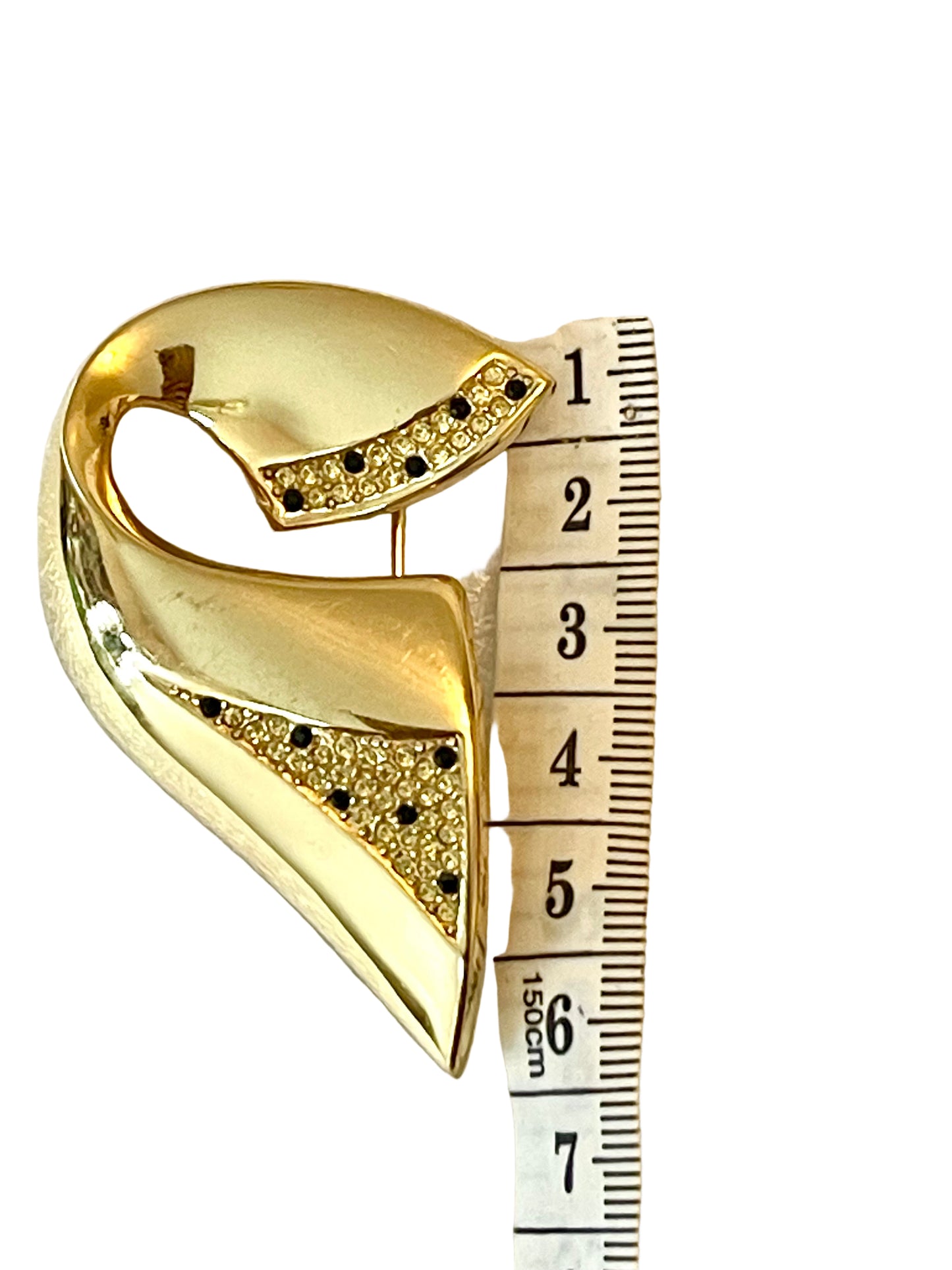 Vintage Christian Dior gold-tone sculptural brooch decorated with black and clear rhinestones, displayed with a measuring tape