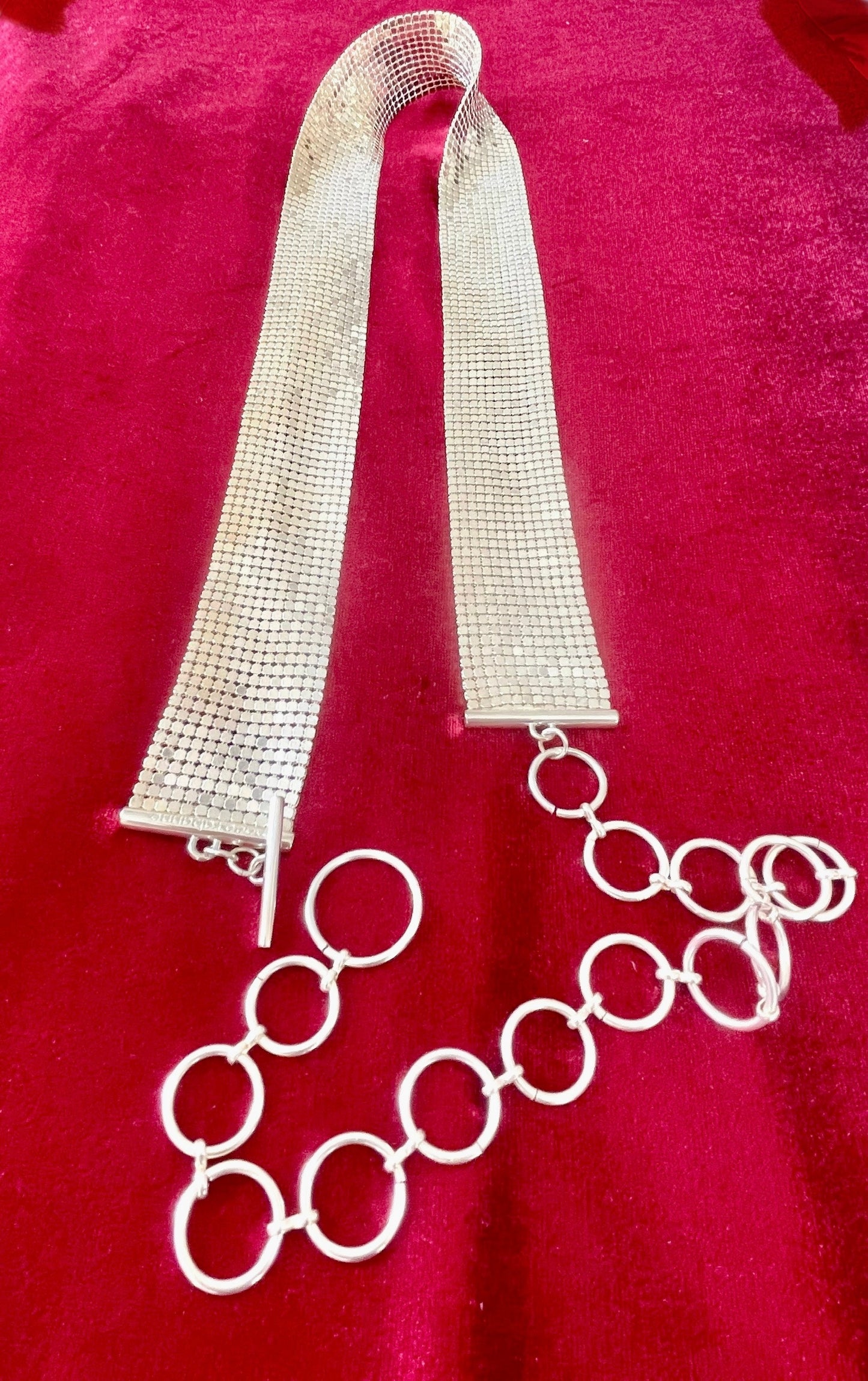 Close up on vintage silver Paco Rabanne mesh belt on red velvet background.