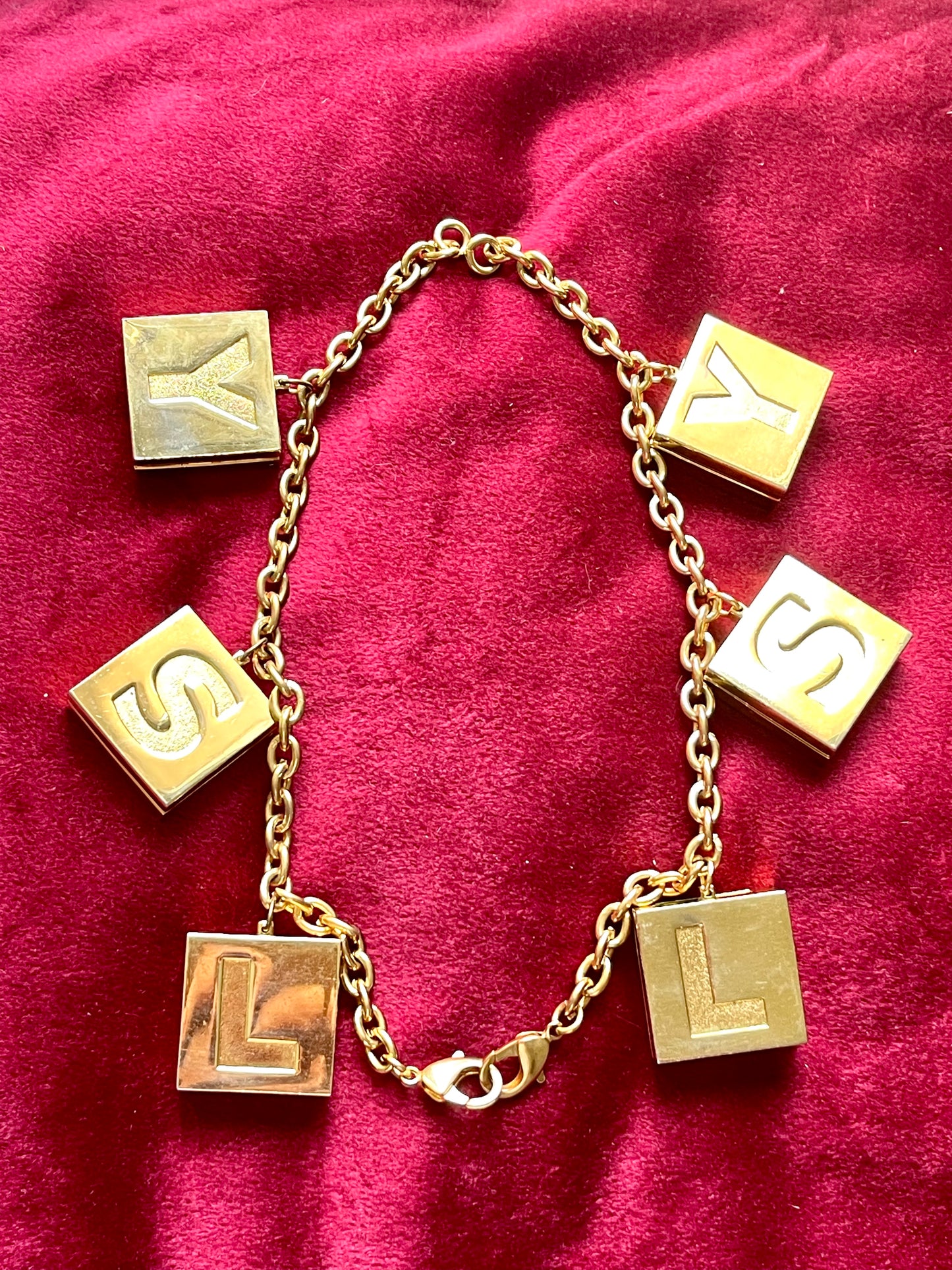 Connected two YSL Yves Saint Laurent vintage 2000 makeup bracelet very good condition on red velvet background as a necklace