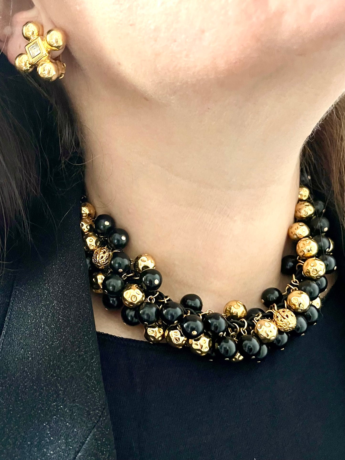 Vintage Yves Saint Laurent beaded necklace with black and gold beads, woven into braided black cotton cords, displayed on a black background worn by model