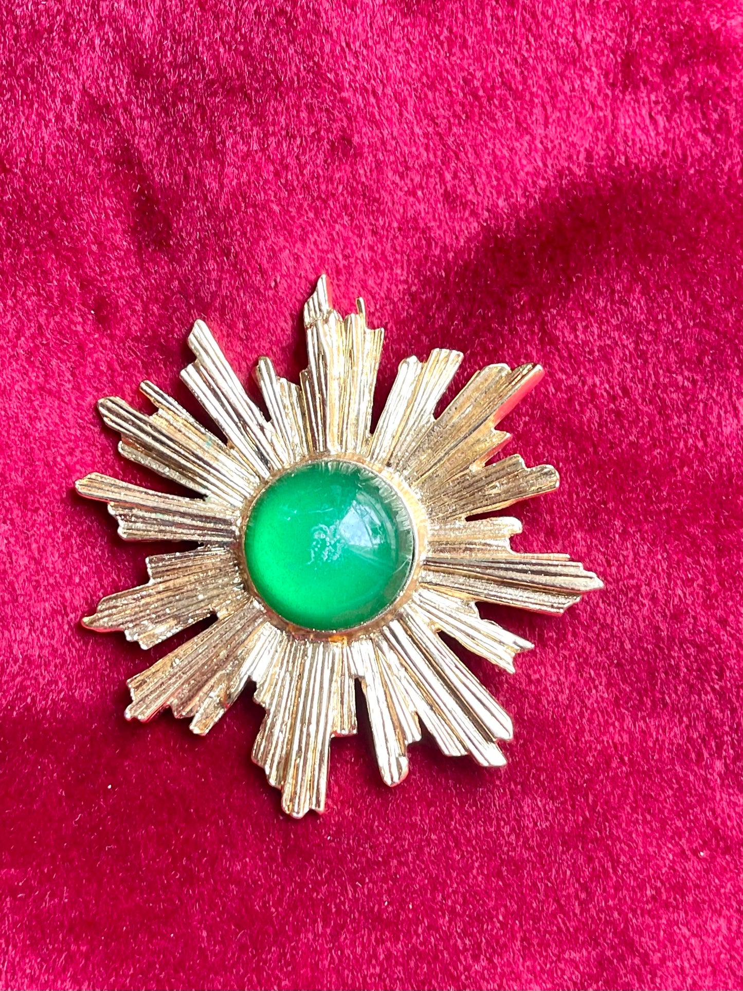 Rare Vintage Yves Saint Laurent 1980s gold-tone sunburst brooch with green cabochon center on ted velvet background