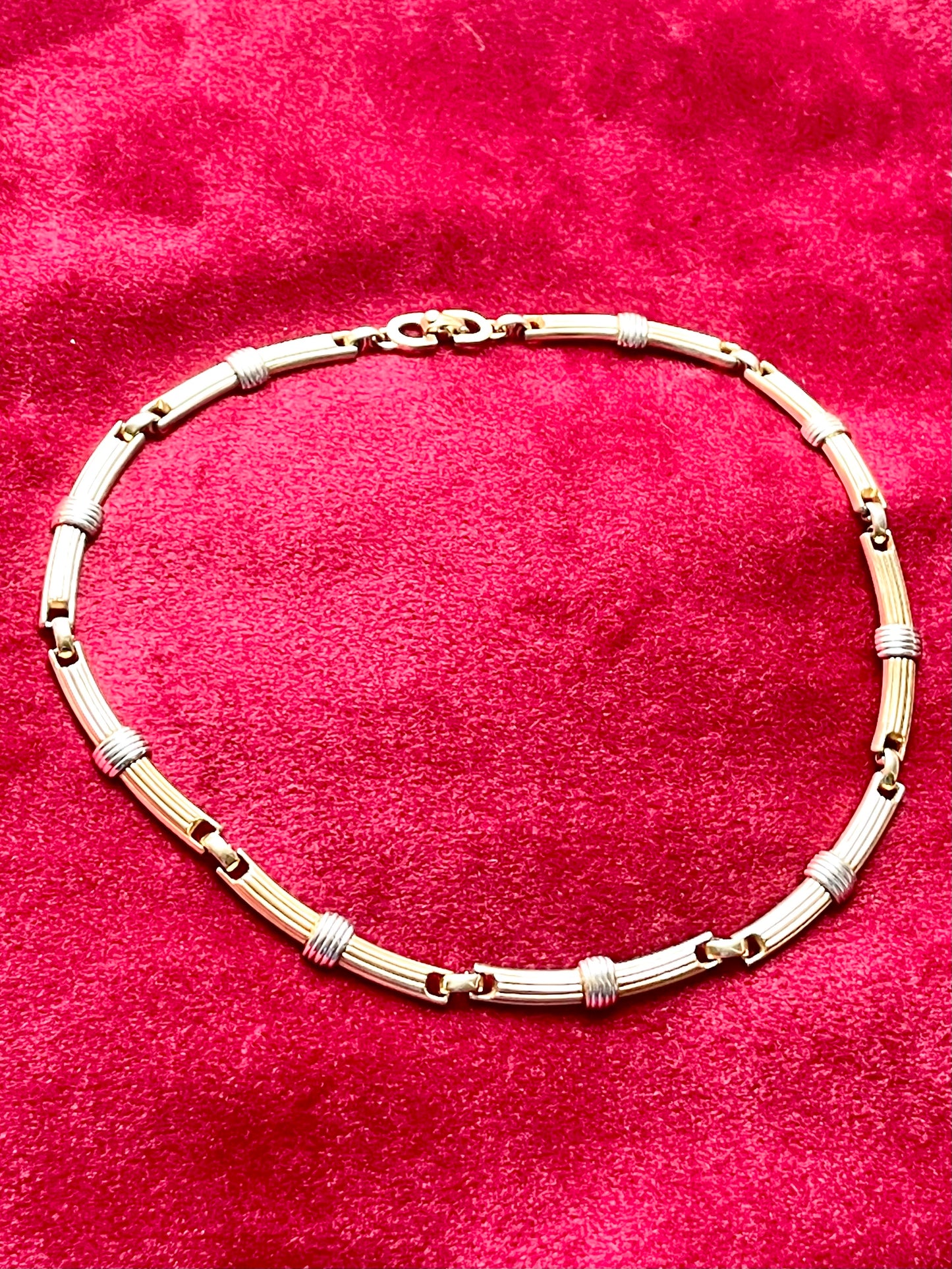Vintage Christian Dior two-tone necklace with ribbed accents displayed on a red velvet background