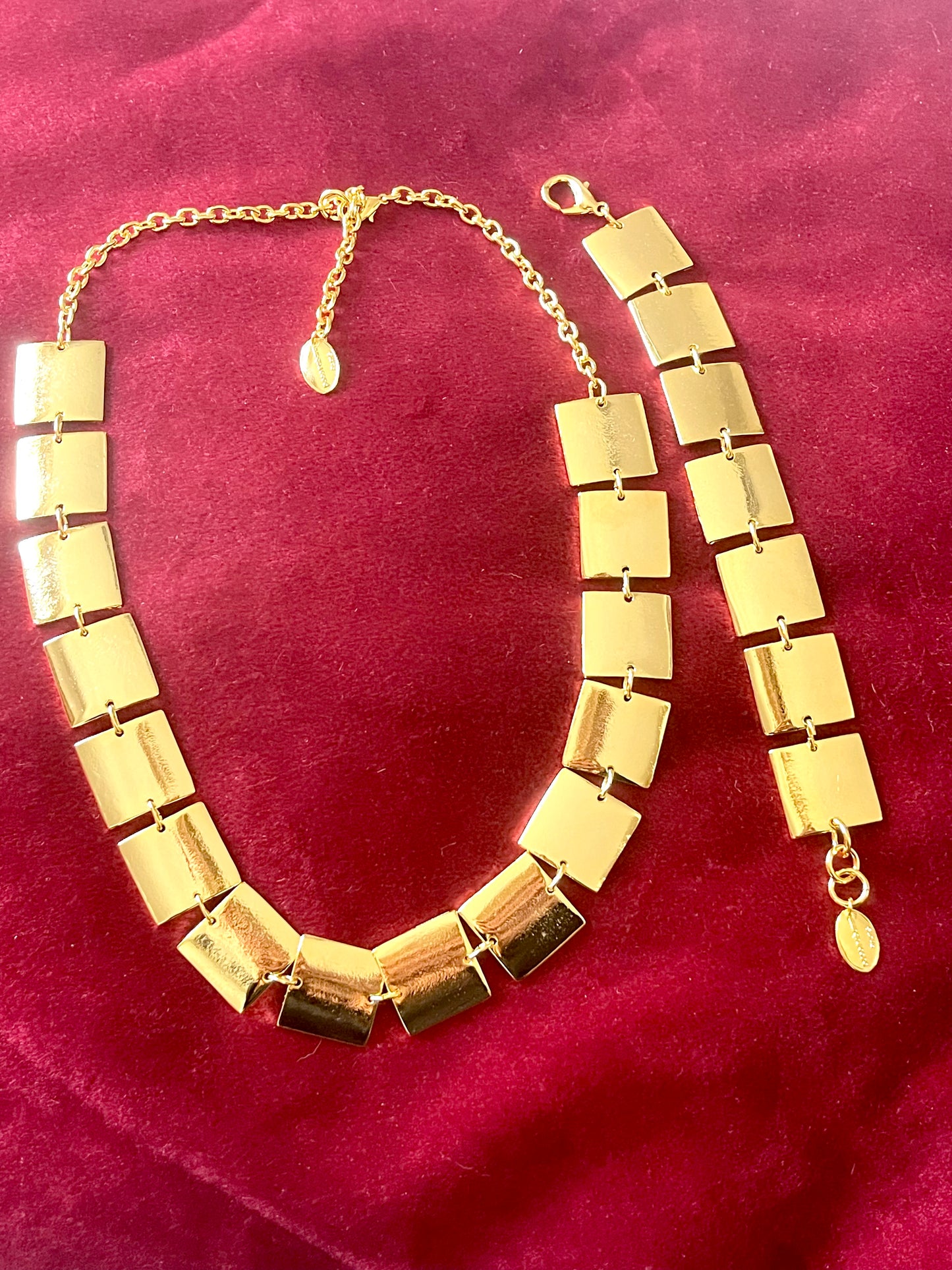 Close up of Iconic Paco Rabanne vintage gold plated jewelry set , bracelet- necklace refurbished 18KG flat on a red velvet background