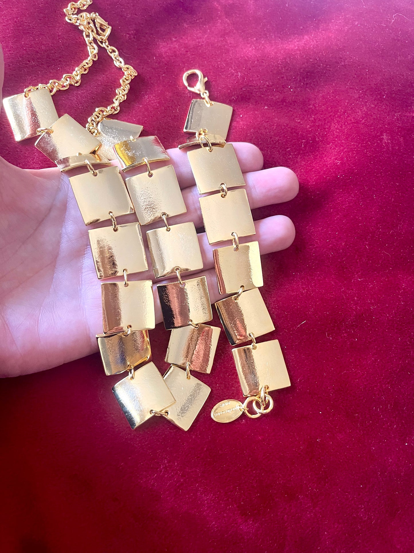 Upper view Close up of Iconic Paco Rabanne vintage gold plated jewelry set , bracelet- necklace refurbished 18KG on hand and red background