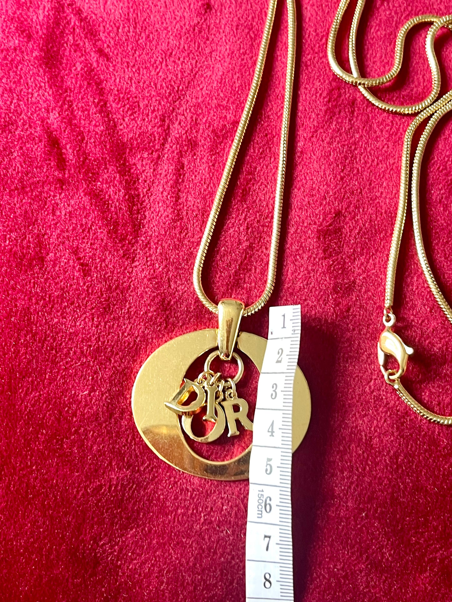 Detailed view of authentic 1990s–2000s Christian Dior logo necklace. Gold-tone finish, statement pendant.