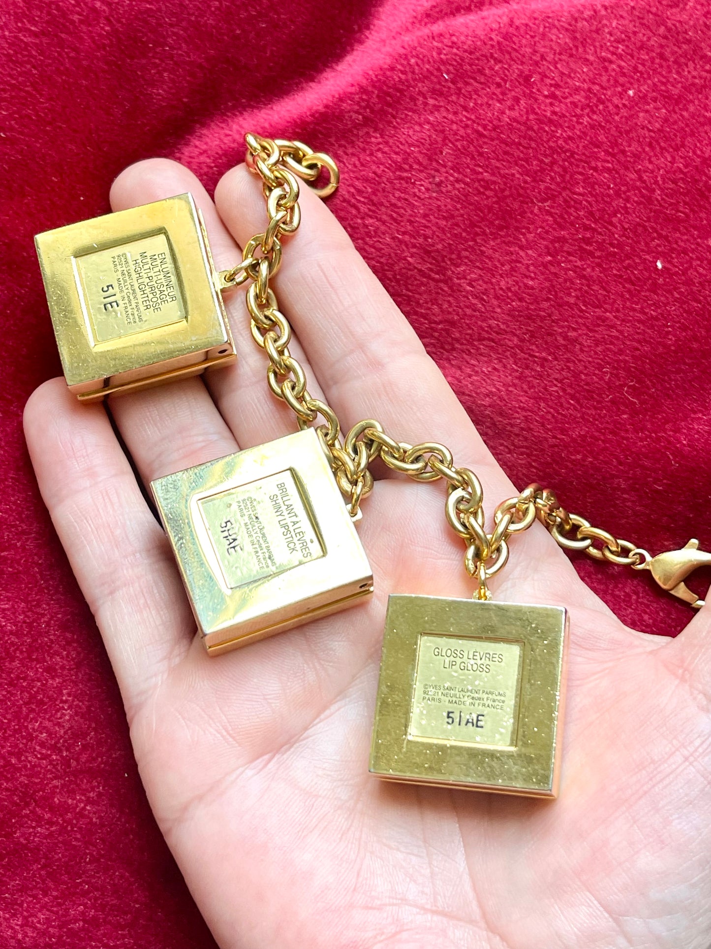 Back view on hand YSL cubic charms Yves Saint Laurent vintage 2000 makeup bracelet very good condition on red velvet background