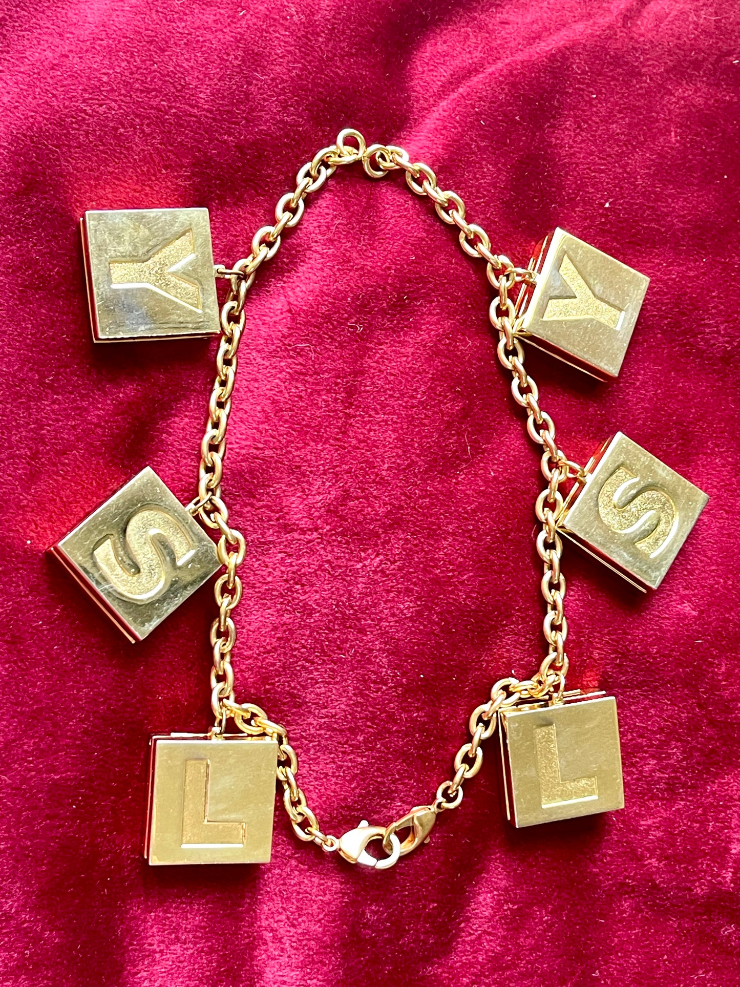 Two YSL Yves Saint Laurent vintage 2000 makeup bracelet very good condition on red velvet background connected as a necklace