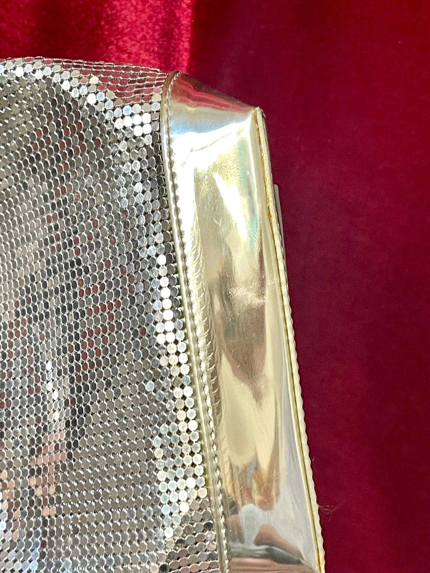 base view of Paco Rabanne silver shoulder/wrist bag with both straps shown, on red velvet fabric background.