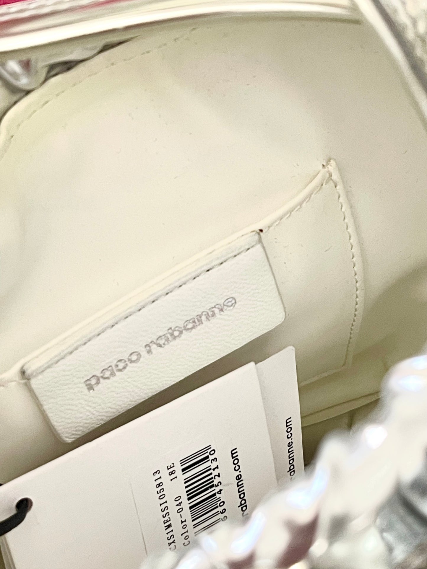 Signature view of Paco Rabanne silver shoulder/wrist bag with both straps shown, on red velvet fabric background.