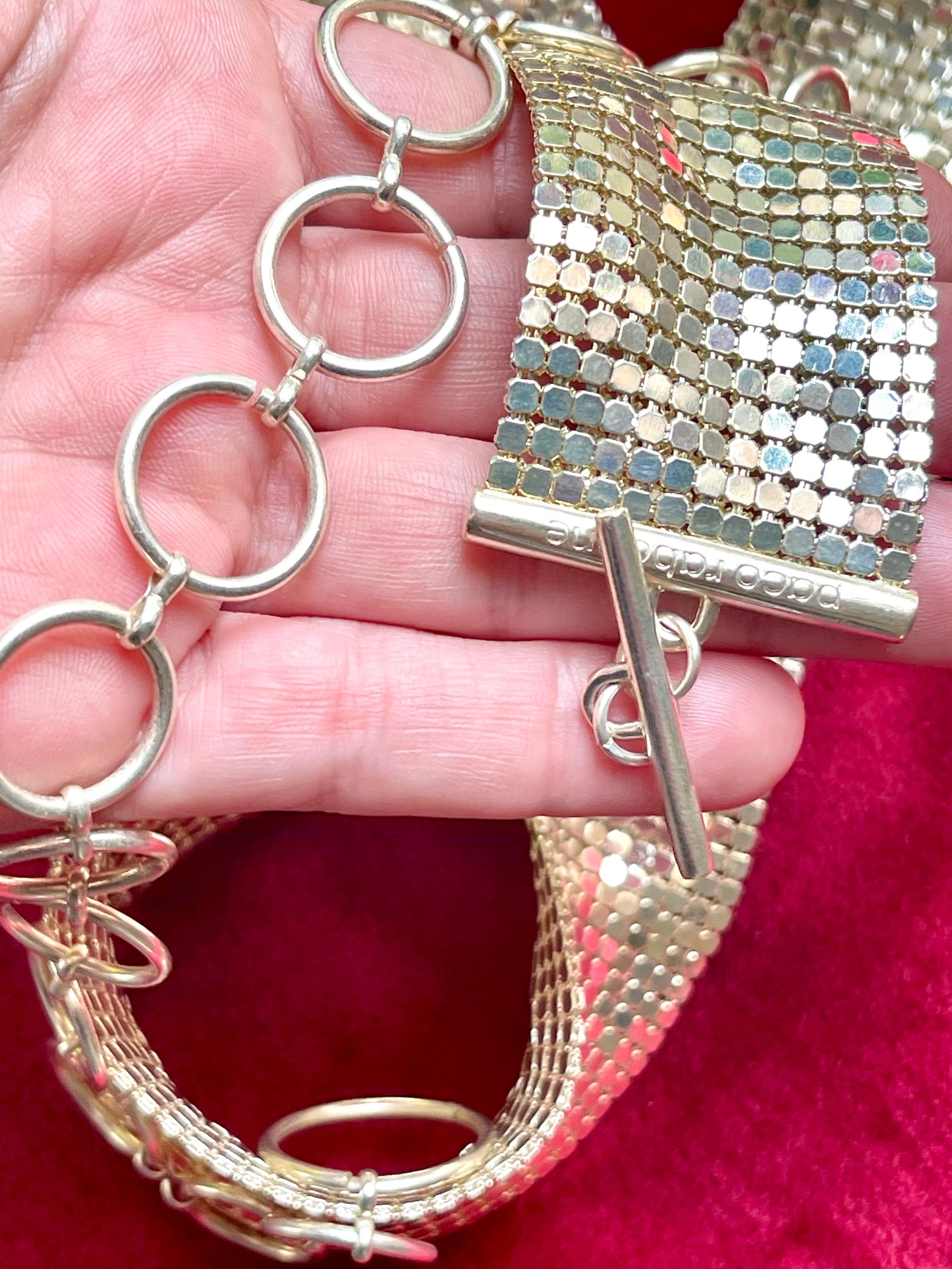 Close up view held by hand of adjustable hoop links , signature and toggle clasp belt from vintage Paco Rabanne mesh