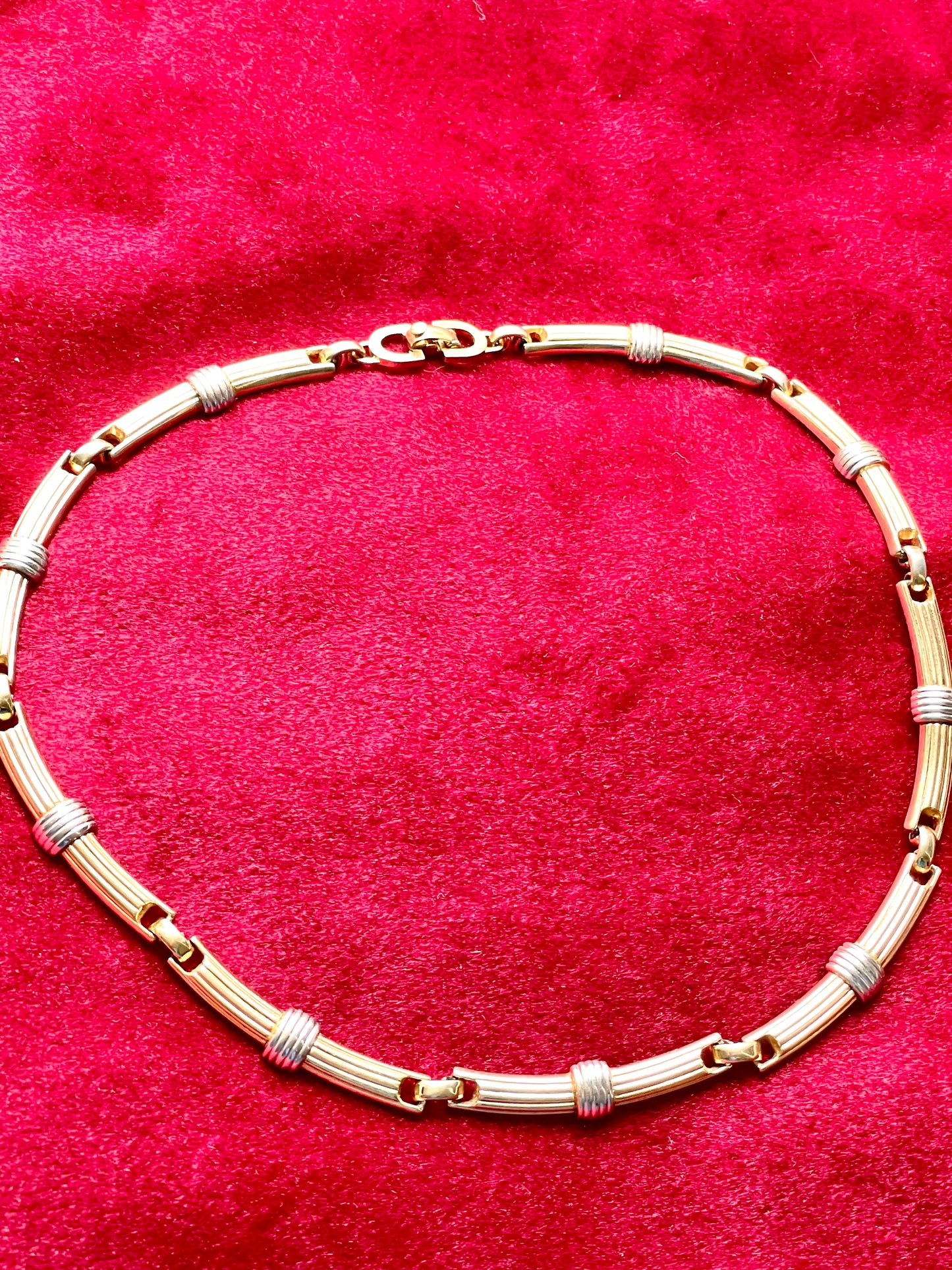Vintage Christian Dior two-tone necklace with ribbed accents displayed on a red velvet background