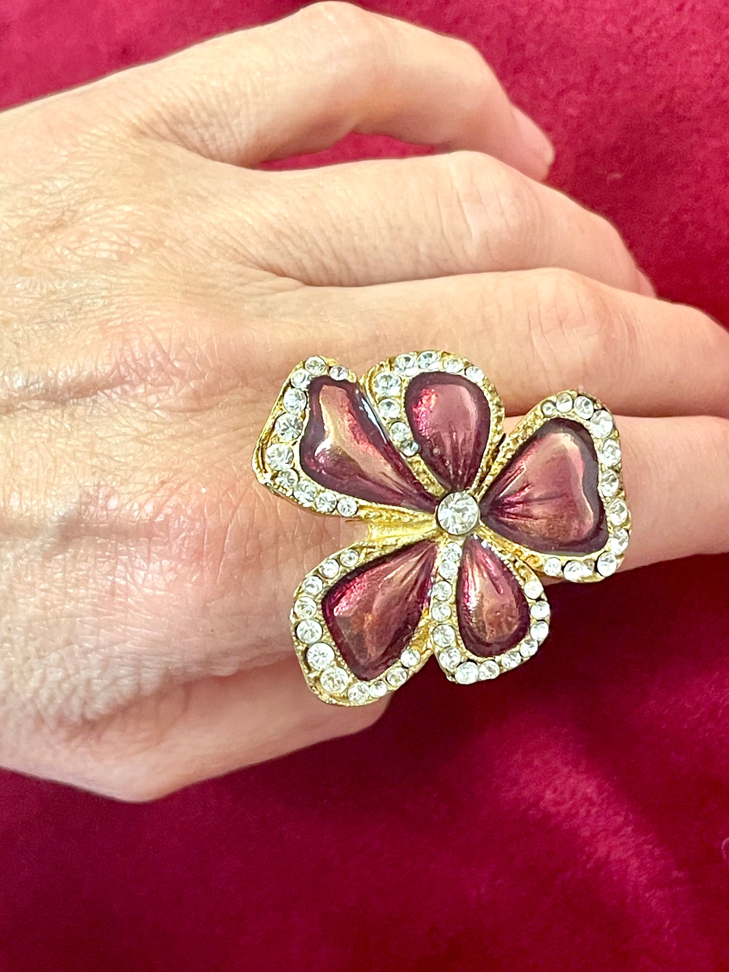 Yves Saint Laurent vintage floral ring on hand, featuring metallic pink enamel petals and crystal accents can be worn on different fingers