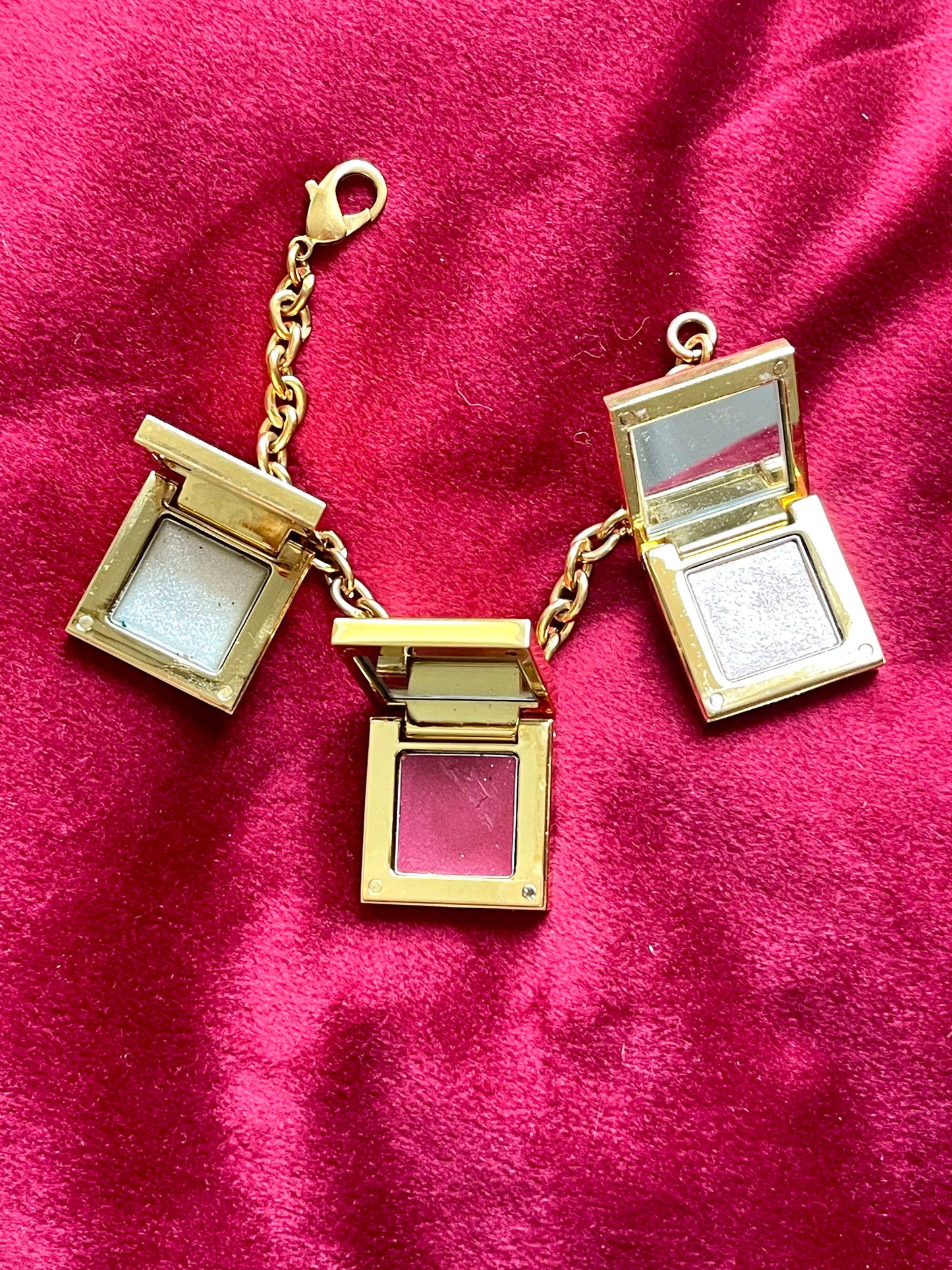 Showing inside makeup and mirrors of YSL charms Yves Saint Laurent vintage 2000 makeup bracelet very good condition on red velvet background