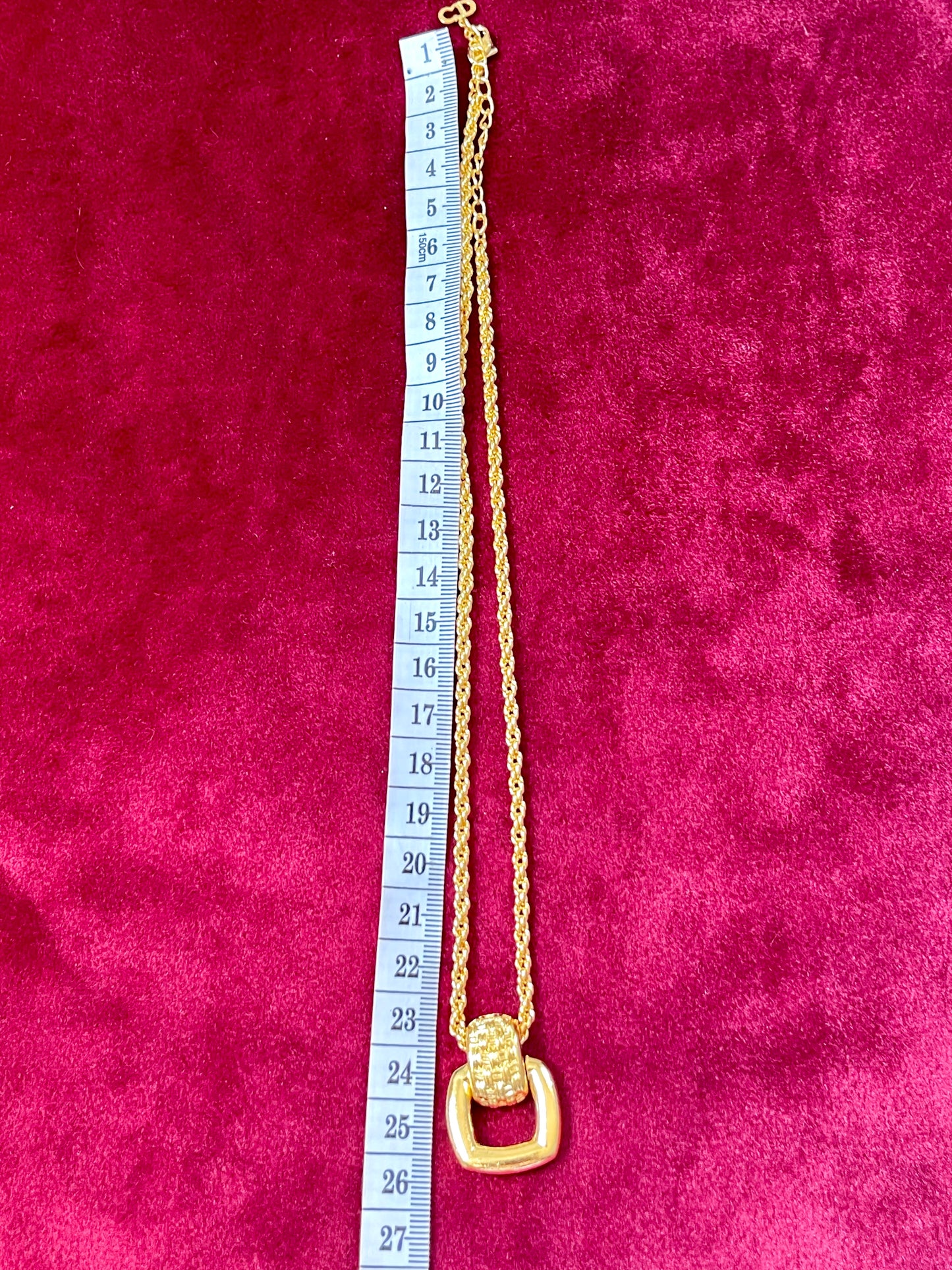 Refurbished vintage Dior gold pendant necklace laid flat on red velvet with measuring tape showing approx. 25 cm length