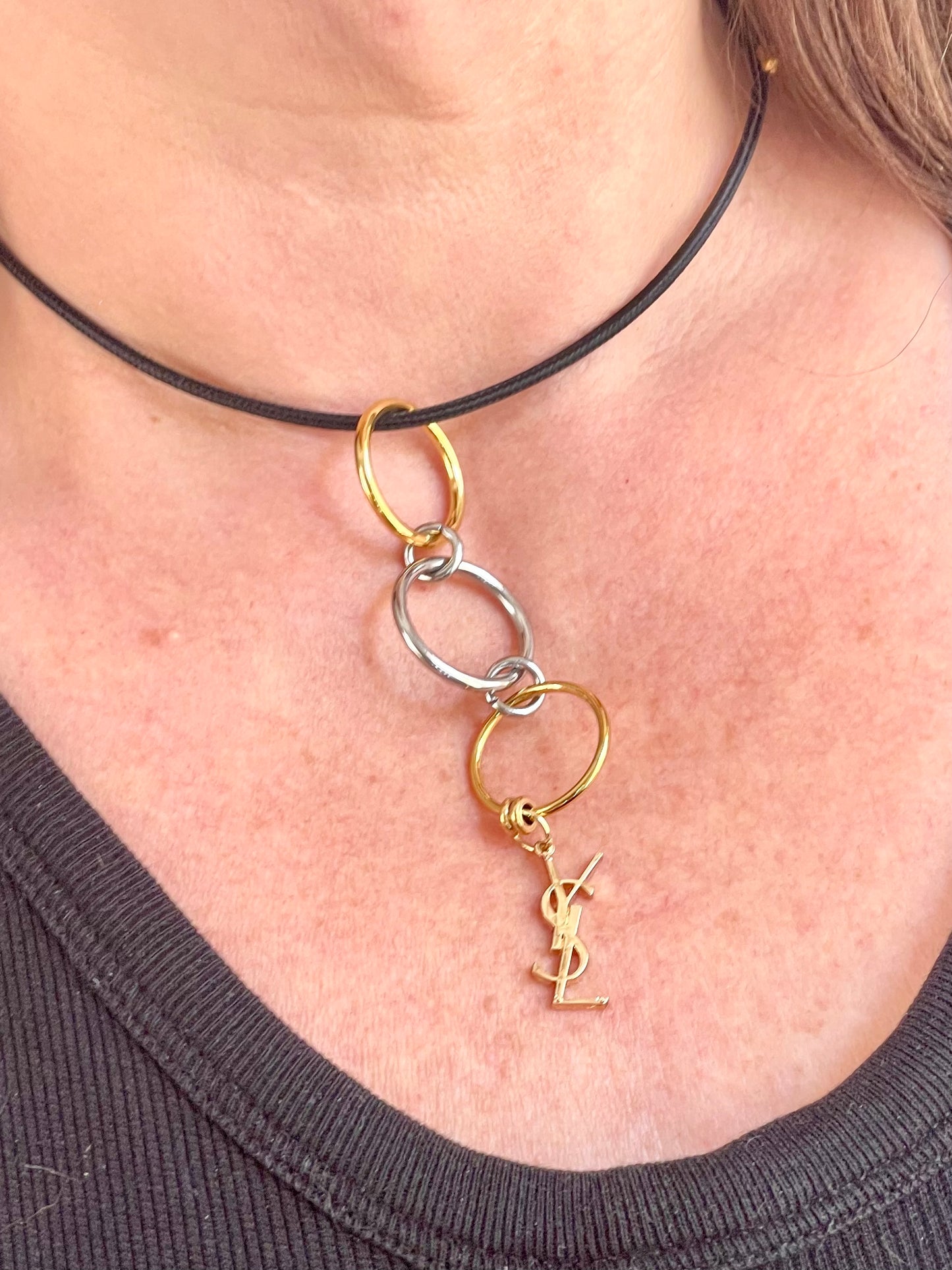 Worn by model choker close up view Yves Saint Laurent authentic charm as a ring pendant and bracelet with magnetic black cord stainless steel gold silver tone