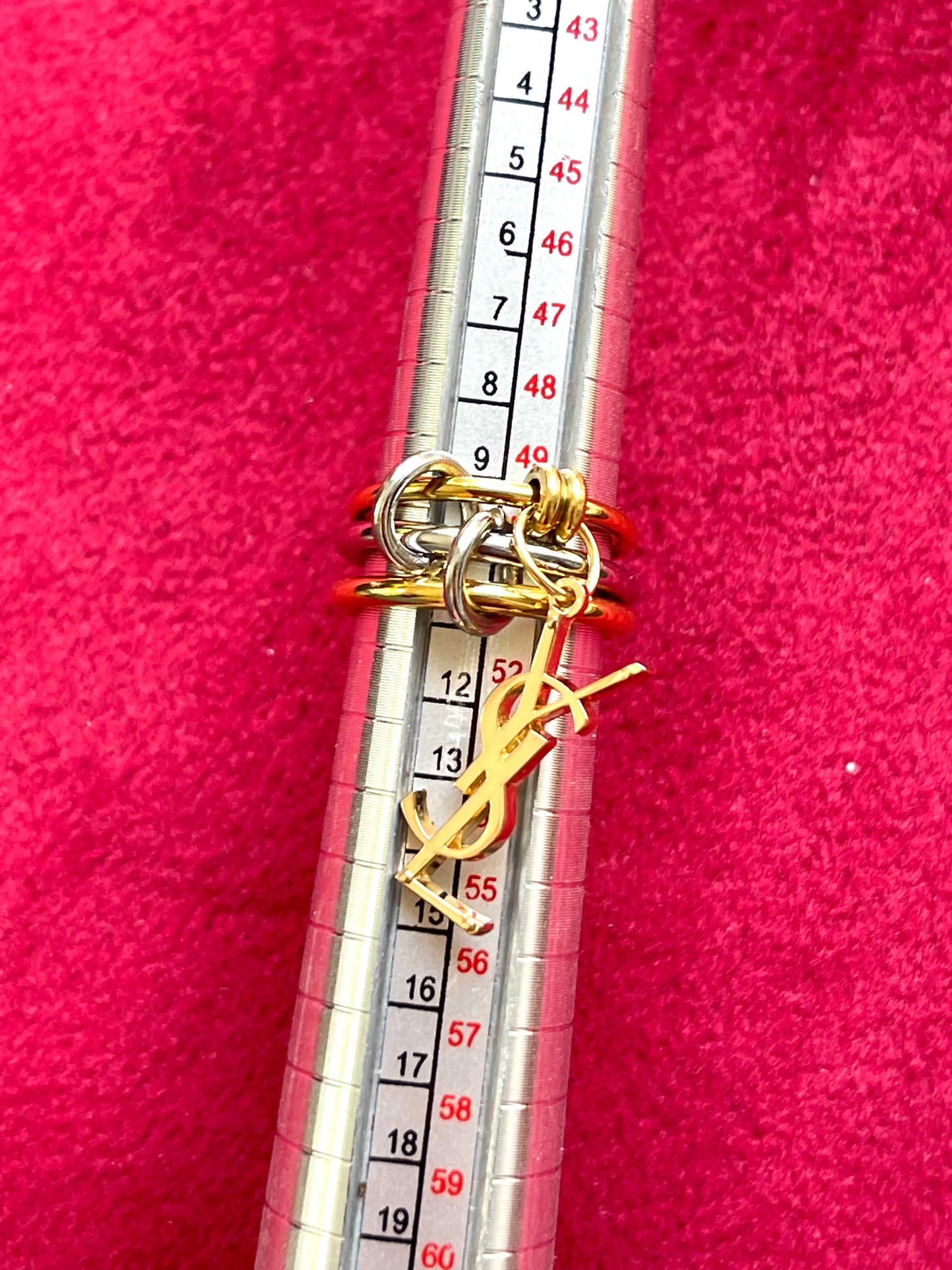 Size 50 on measure bar close up view Yves Saint Laurent authentic charm as a ring pendant and bracelet with magnetic black cord stainless steel gold silver tone