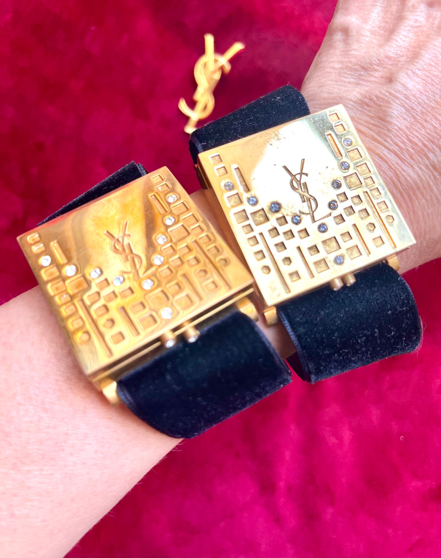 Side view of two Fashion Bracelet makeup Yves Saint Laurent vintage 2000 displayed with YSL pins on a red velvet background
