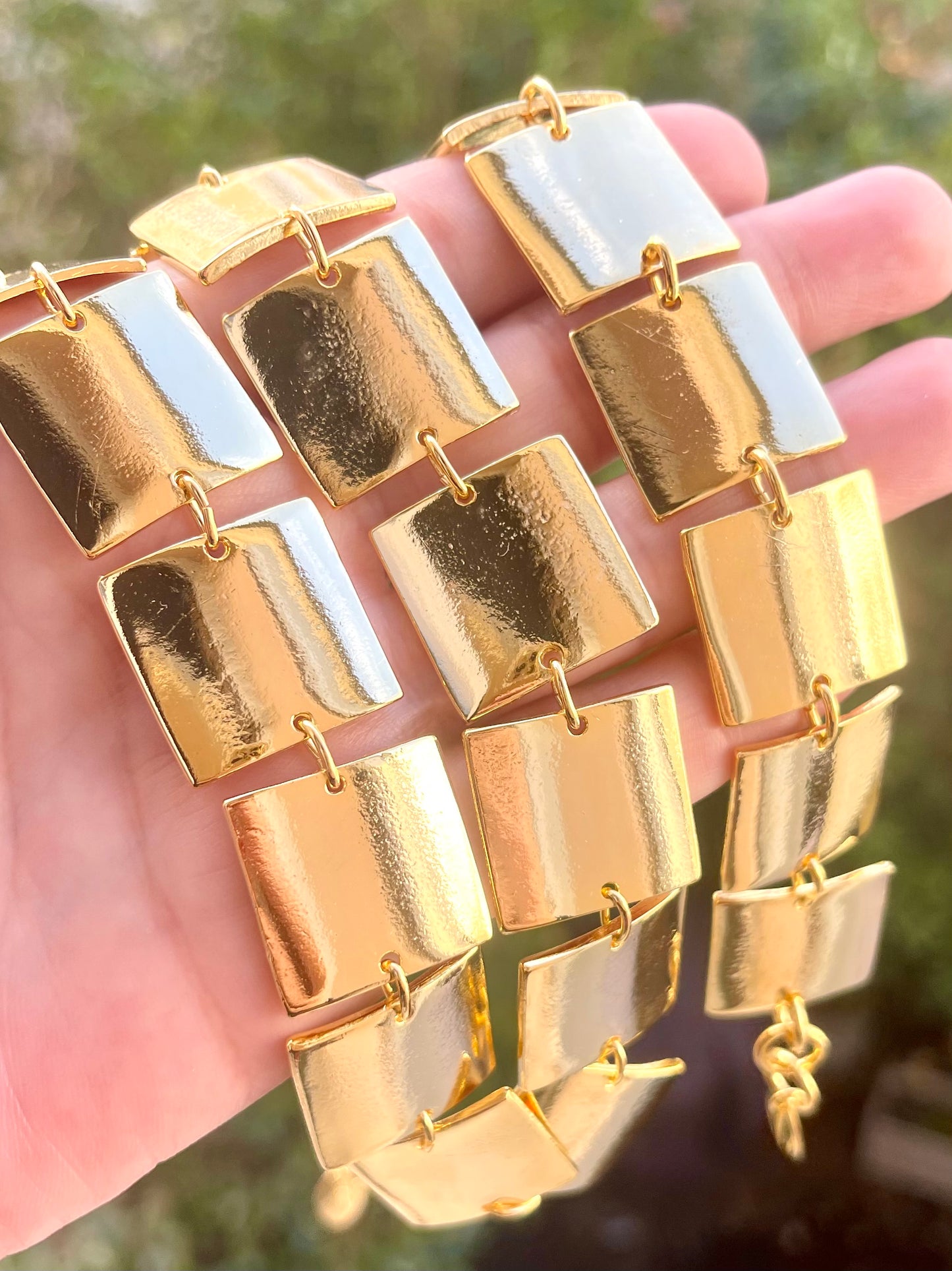 Close up in natural light of Iconic Paco Rabanne vintage gold plated jewelry set , bracelet- necklace refurbished 18KG held by hand