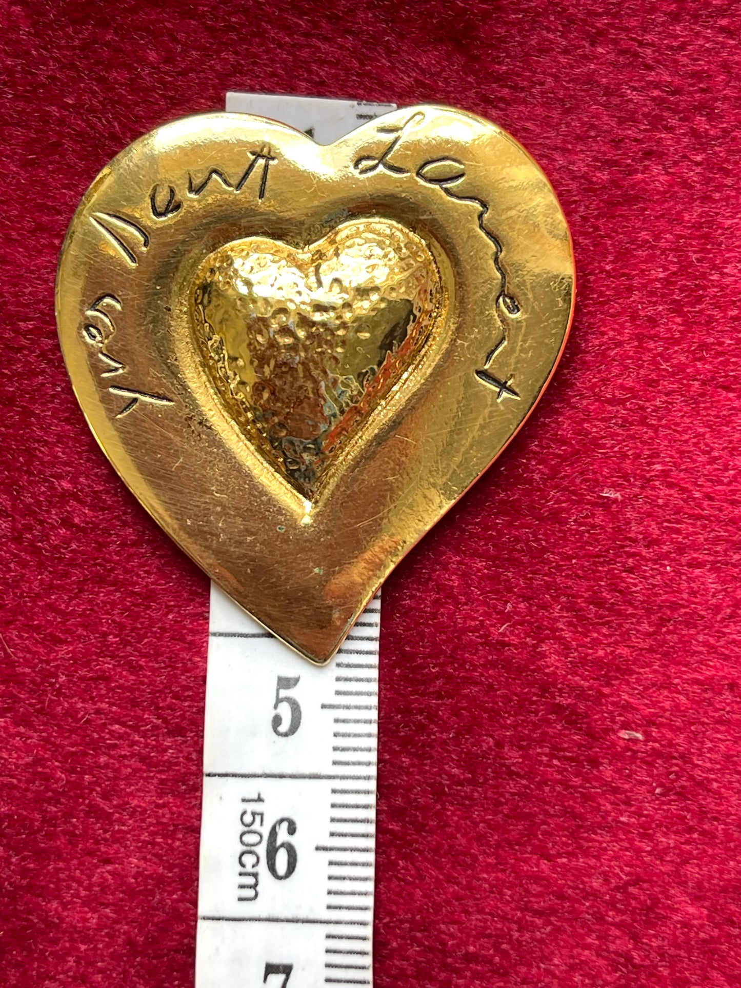 Using measuring tape showcasing the size of Yves Saint Laurent vintage gold plated repurposed 18KG Arty Heart brooch on red velvet background