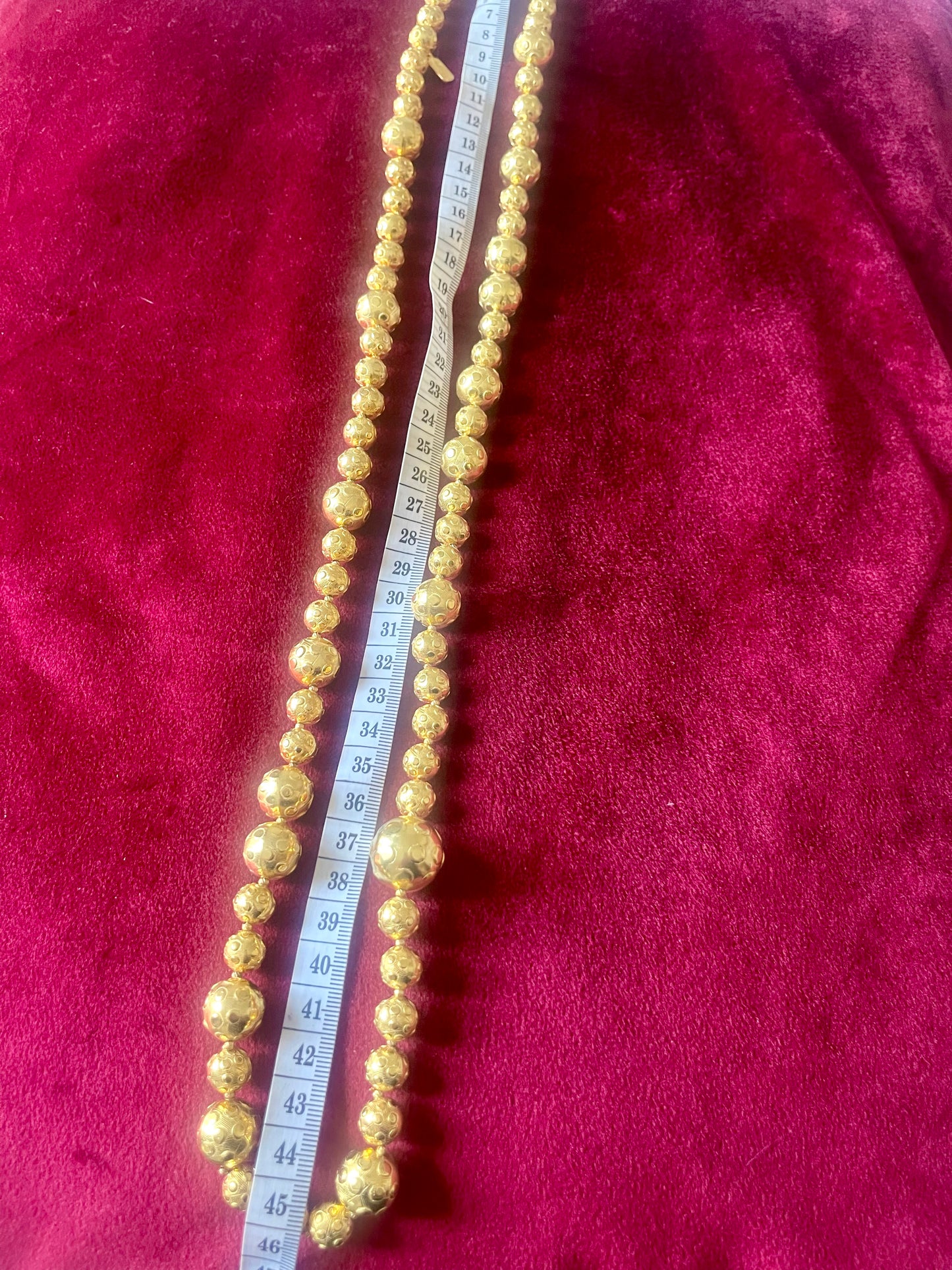 Full view of 45 cm Yves Saint Laurent vintage gold-tone necklace with graduated beads using a measuring tape