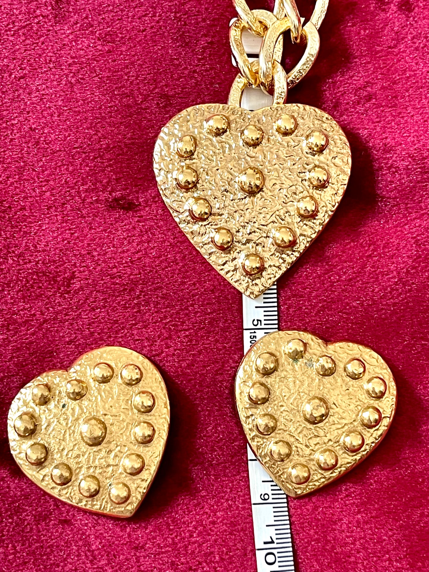 Measuring tape showing all dimensions of Vintage 80s Yves Saint Laurent YSL jewelry rare set . Heart earrings - pendant brooch with a gold plated chain necklace on a red velvet background