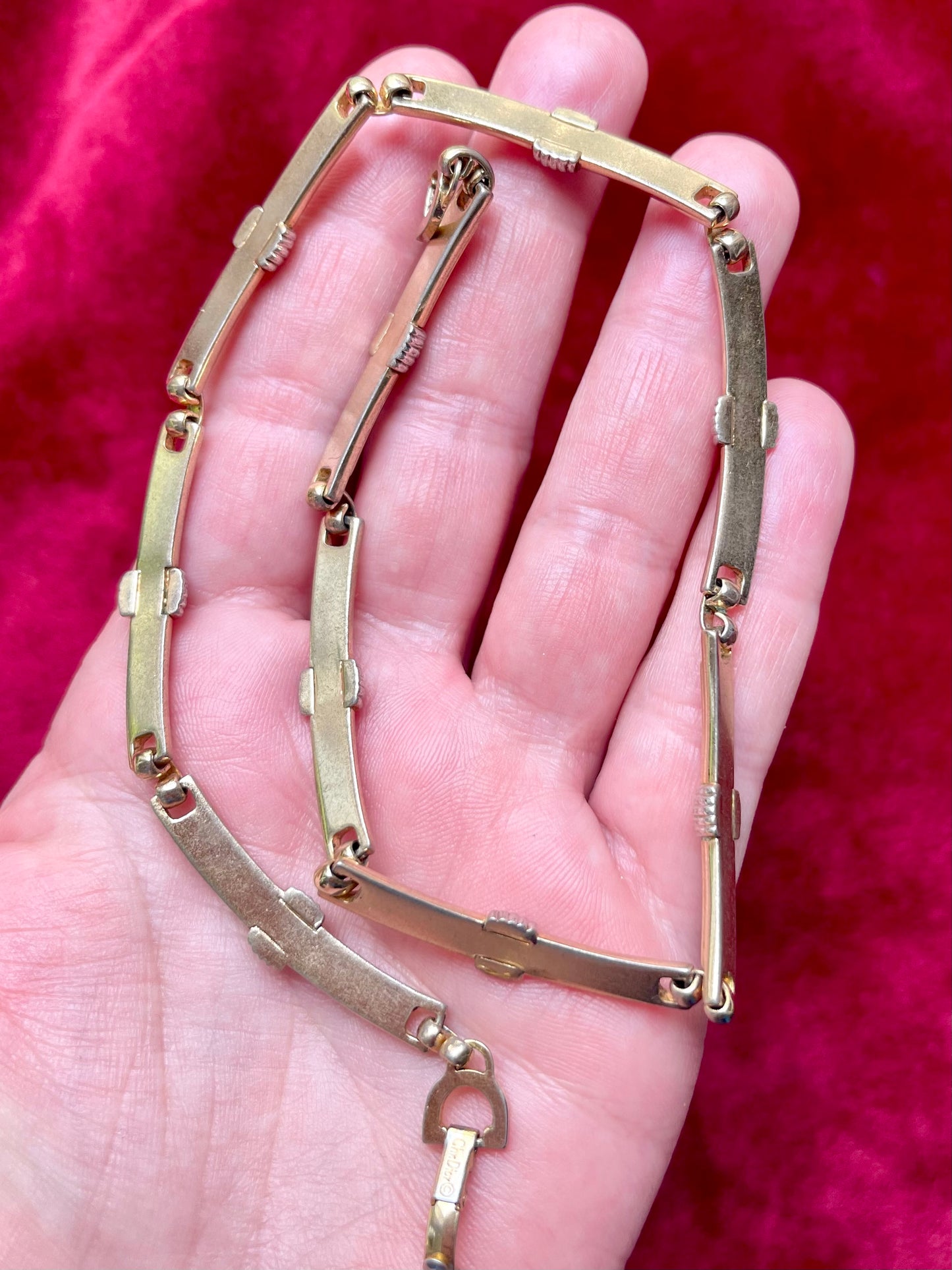 Back side on skin tone Vintage Christian Dior two-tone necklace with ribbed accents displayed on a red velvet background