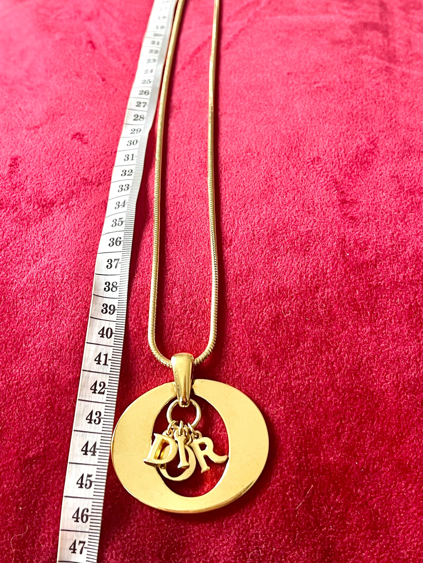 Detailed view of authentic 1990s–2000s Christian Dior logo necklace. Gold-tone finish, statement pendant.