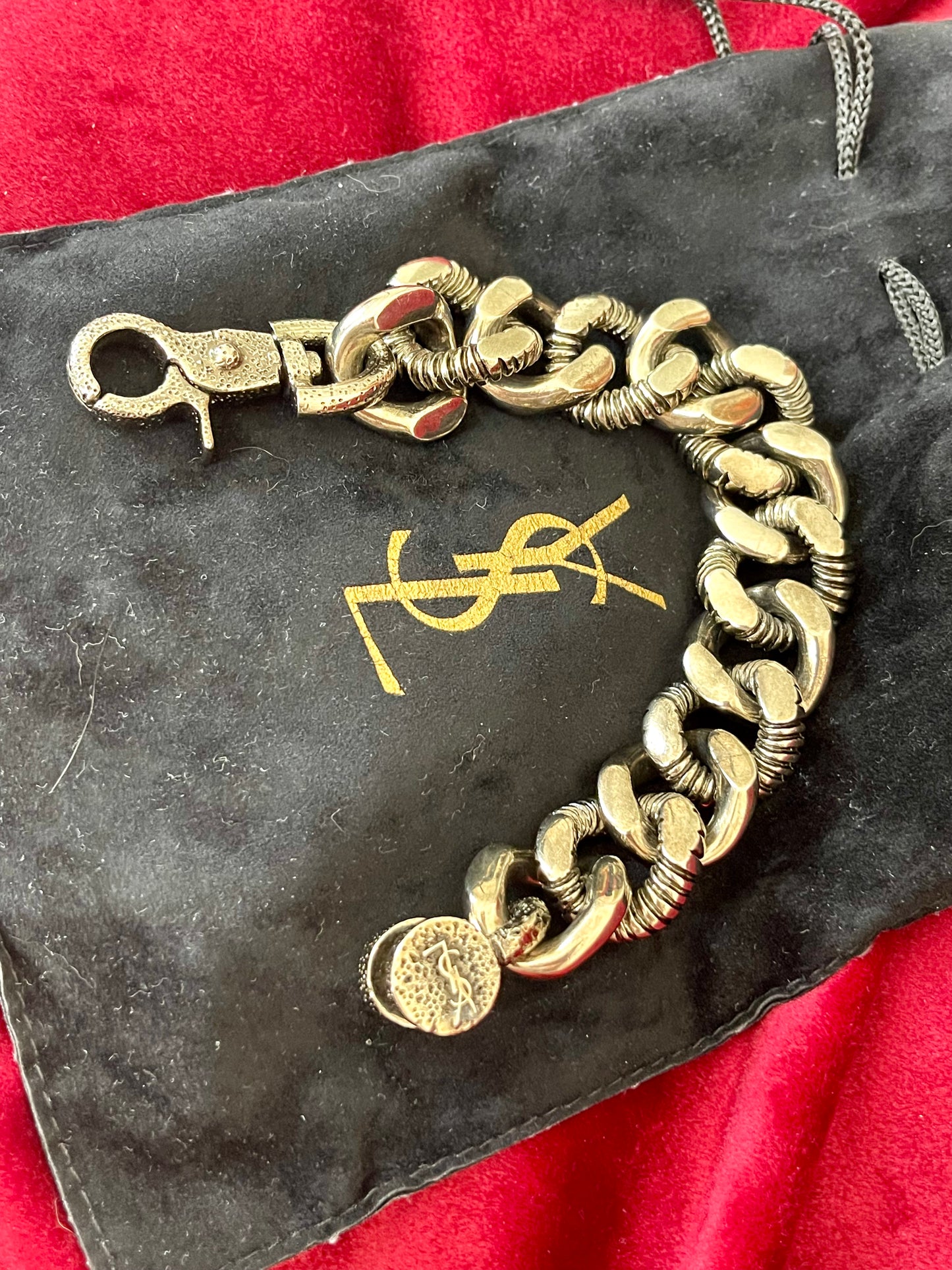 YSL chunky chain displayed draped on a sleek black Yves Saint Laurent pouch, showcasing bronze and grey tones