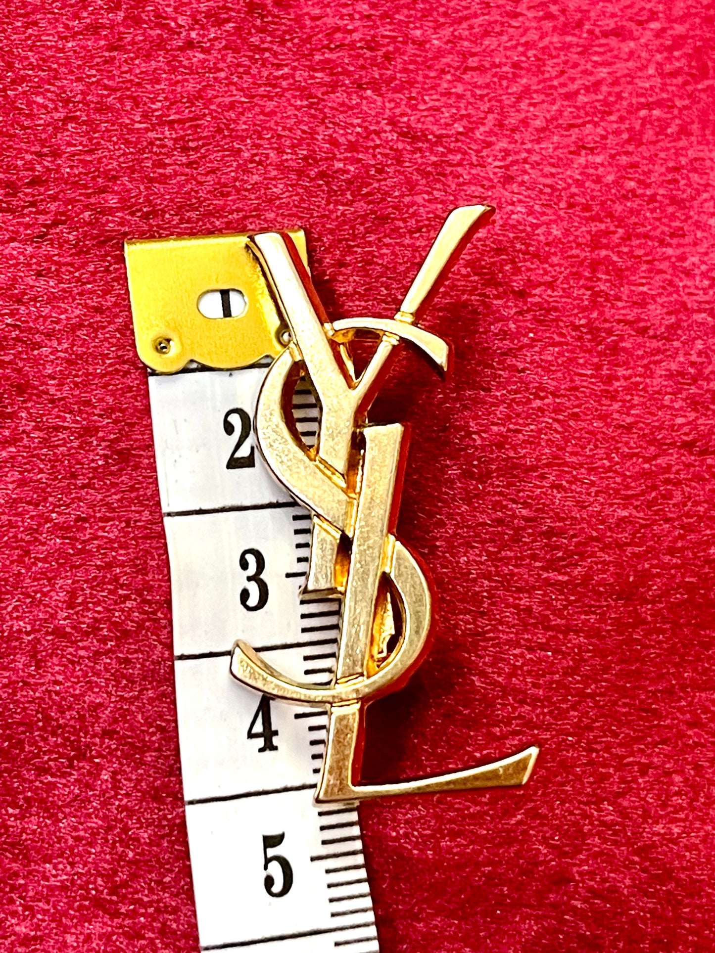 Broche Yves Saint Laurent con letras en tono dorado