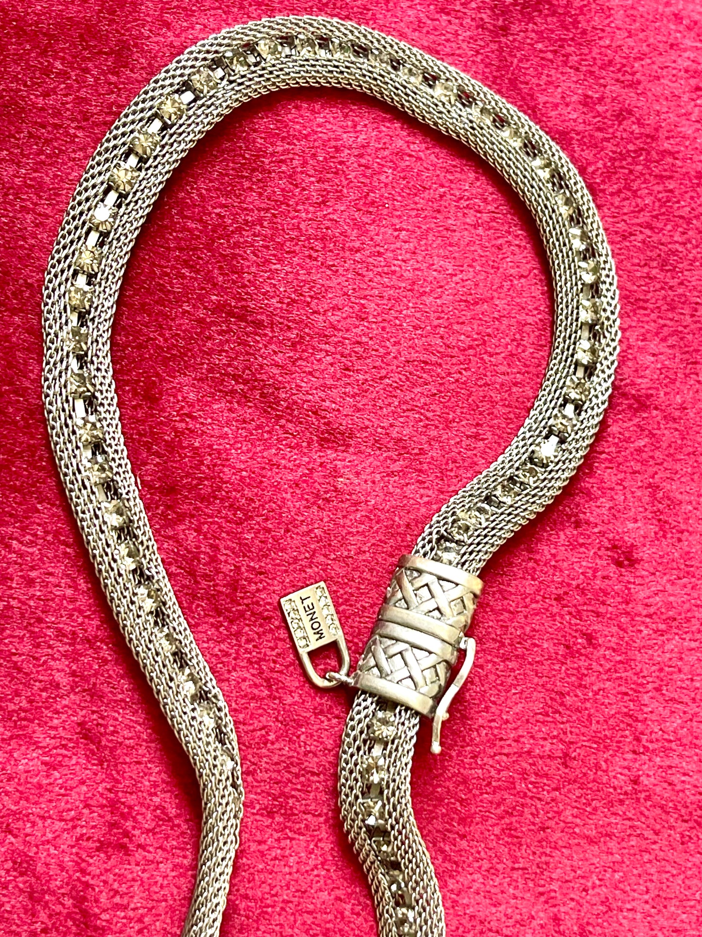 Close up Monet Yves Saint Laurent silver metal necklace rhinestone tagged chocker on red velvet background
