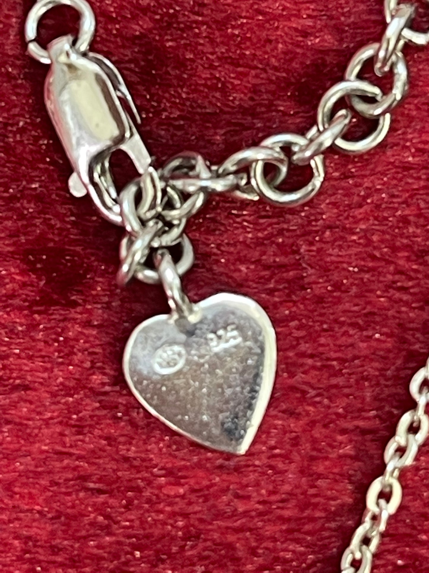 Vintage Dior solid silver heart bracelet displayed on rich red velvet, showcasing 925 stamped
