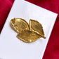 Vintage Yves Saint Laurent 80s 90s gold tone leaf brooch excellent condition on white and red background 