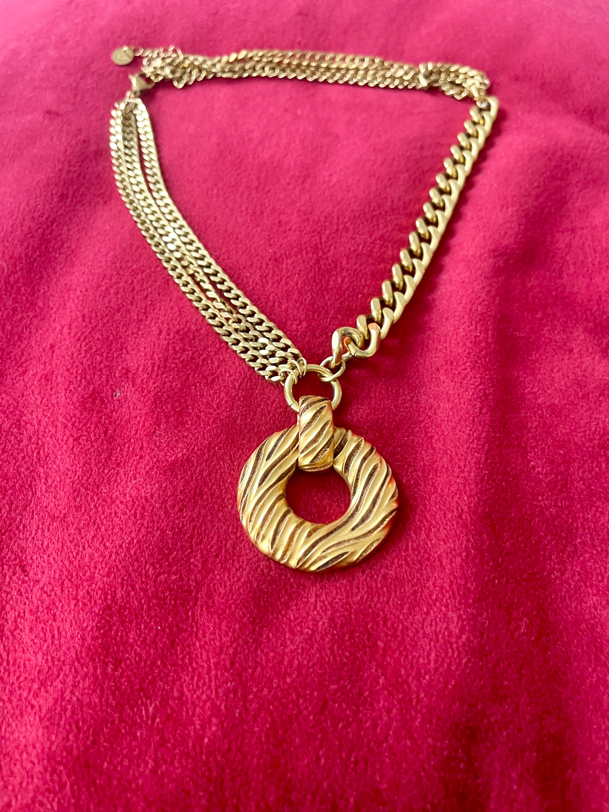 Gold tone 80s Yves Saint Laurent vintage pendant  stainless steel chain necklace  on red velvet background 