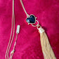 Gold-plated vintage necklace with black resin heart pendant and attached Yves Saint Laurent gold tassel charm displayed on red velvet.