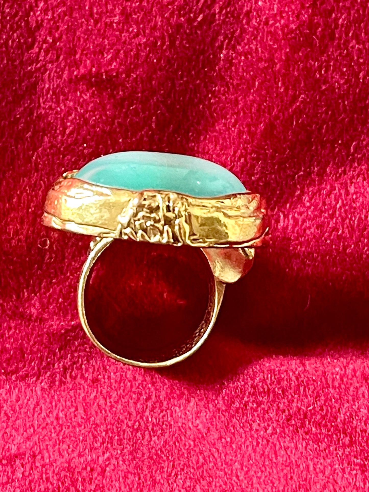 Side profile of a vintage YSL ring showing the intricate textured gold band and raised turquoise nacre centerpiece.authentic signed Yves Saint Laurent 