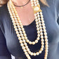 Close-up of YSL faux pearl necklace clasp worn on neck, highlighting the gold-tone sculptural design and domed pearl centerpiece
