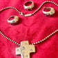 Vintage YSL silver jewelry set displayed on red fabric: silver earrings, cross pendant necklace on beaded chain and ring 