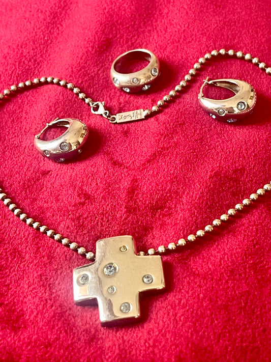 Vintage YSL silver jewelry set displayed on red fabric: silver earrings, cross pendant necklace on beaded chain and ring 