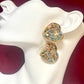 Pair  gold-tone vintage Yves Saint Laurent heart-shaped clip-on earrings decorated with multi-colored crystals, displayed on a mannequin on a red background