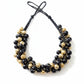 Vintage Yves Saint Laurent beaded necklace with black and gold beads, woven into braided black cotton cords on white background 
