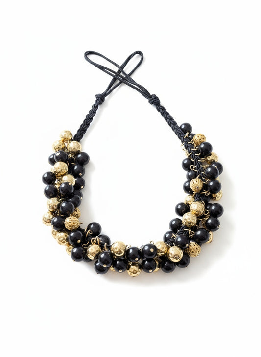 Vintage Yves Saint Laurent beaded necklace with black and gold beads, woven into braided black cotton cords on white background 